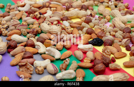 Assorted nuts scattered on a colorful paper background High angle view Stock Photo