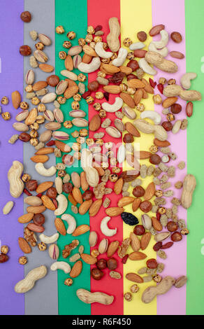 Assorted nuts scattered on a colorful paper background top view Stock Photo