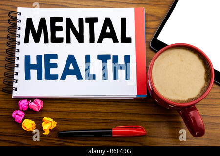 Handwritten text showing Mental Health. Business concept writing Anxiety Illness Disorder Written on notepad note paper, old black wooden background in office view with pen coffee and tablet Stock Photo