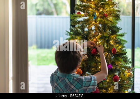 Boy decorating a Christmas tree, South Australia. Focus on hands Stock Photo