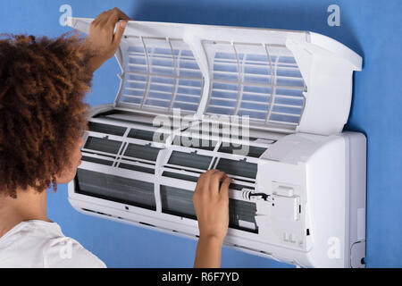 Woman Checking Air Conditioner At Home Stock Photo