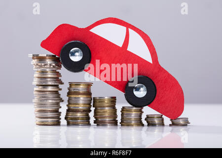 Red Car Over Stacked Coins Stock Photo