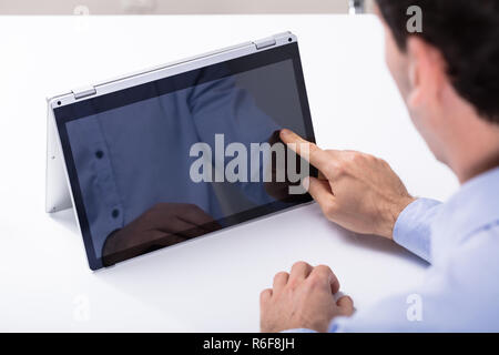 Man Touching Hybrid Laptop Screen With Finger Stock Photo