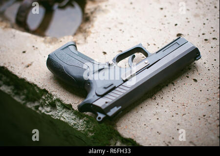 Black gun lying on the concrete Stock Photo