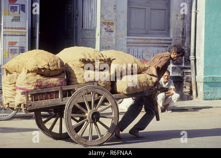 Man pulling wooden handcart with sacks full , India , Asia Stock Photo