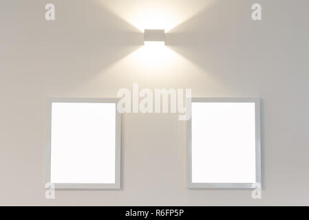 Two blank picture frames on wall with light Stock Photo