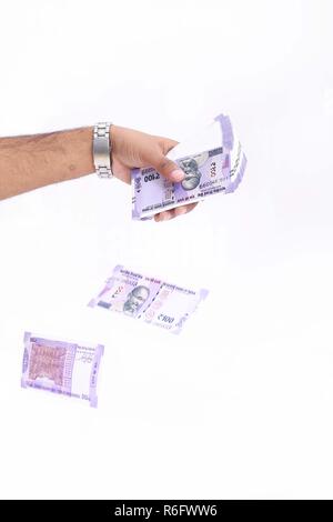 Man hand is throwing new Indian currency. Isolated on the white background. Stock Photo