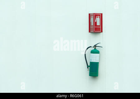 Green fire extinguisher and the fire symbol on a white wall. Stock Photo