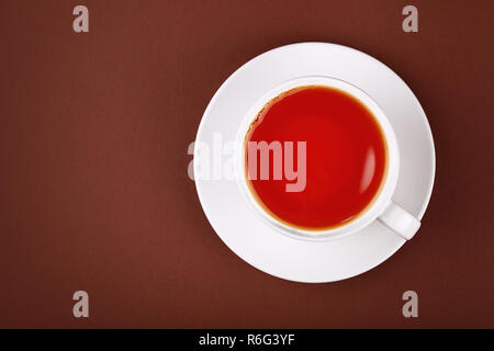 Full white cup of red black tea on brown Stock Photo