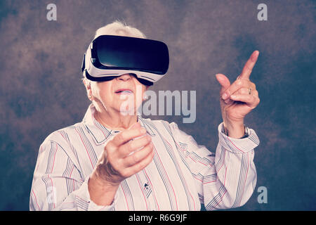 gray hairy elderly woman using virtual reality glasses Stock Photo
