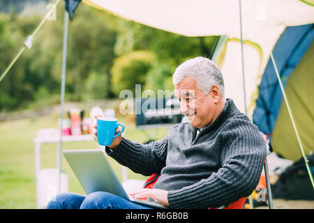 Senior man Using Laptop at Campsite Stock Photo