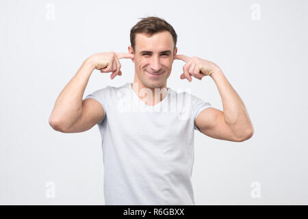 Annoyed mature italian man plugging ears with fingers Stock Photo