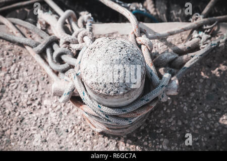 Old mooring bollard with ropes stands on concrete pier in harbor, top view Stock Photo