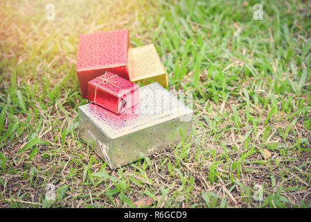 gift box outdoors / colorful of gift box on green field - paper gift wrap various sizes of boxes with red yellow gold and silver color in the park Stock Photo
