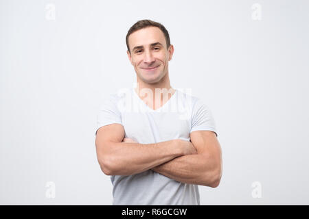 Smiling young man standing with arms crossed against gray background Stock Photo