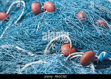Blue fishing net with red floats lays in port. Close-up background photo with selective focus Stock Photo