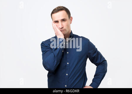Young man feeling pain, holding his cheek with hand, suffering from bad toothache Stock Photo