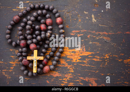 Christian rosary prayer with a cross on old black wooden background with space for text. close-up, top view Stock Photo