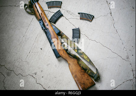 Rifle with cartridges on a textured concrete slab Stock Photo