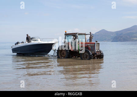 A tractor is used to retrieve and to launch small boats on the Llyn Peninsula in Wales Stock Photo