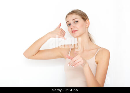 Portrait of happy young woman. Call me back please. Makes phone sign, indicates with index finger directly at camera, wants to speak with someone via  Stock Photo