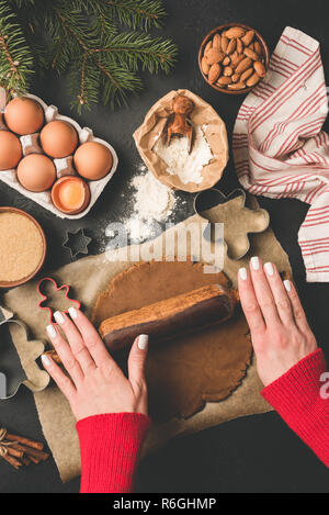 Rolling gingerbread cookie dough. Christmas baking concept. Woman hands using rolling pin to prepare cookie dough. Top view Stock Photo