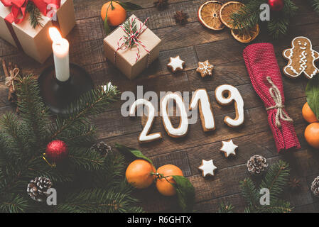 New Year 2019 flat lay composition on wooden background. 2019 numbers made with gingerbread cookies, tangerines, gift box, candles and fir tree frame Stock Photo