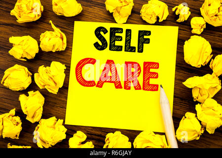 Writing text showing Self Care. Business concept for Taking caring for own Health Written on sticky note paper, wooden background with folded yellow paper meaning thinking Stock Photo