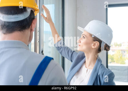 Architect and construction worker checking windows on site Stock Photo