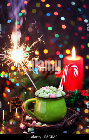 Green mug of hot chocolate with marshmallows, candy cane and sparkler on holiday background, Christmas concept Stock Photo