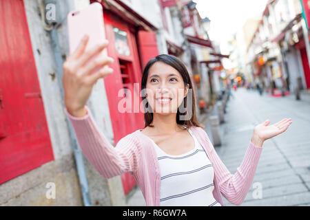 Woman taking selfie with mobile phone in Rua da Felicidade of Macao Stock Photo