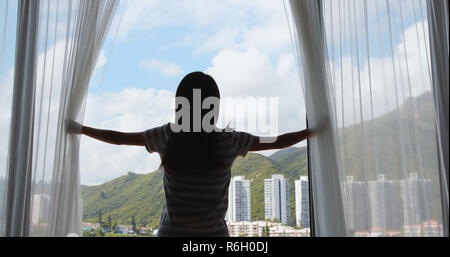 Girl opens the curtains in the morning Stock Photo