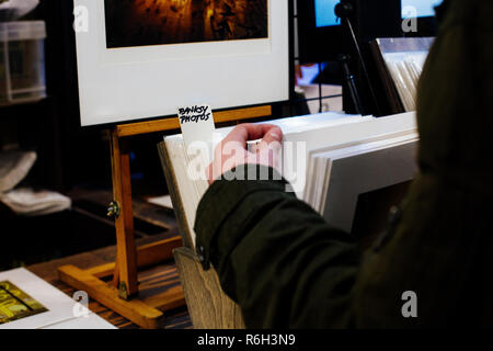 London / UK - March 10, 2018: tourist is looking for Banksy photos in souvenir shop in Covent Garden's Market, London, UK. Covent Garden is popular sh Stock Photo