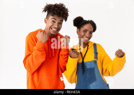 Image of excited african american couple in colorful clothes clenching fists isolated over white background Stock Photo