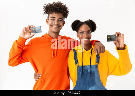 Photo of smiling african american couple standing together and holding credit cards isolated over white background Stock Photo