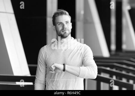 Man athlete on satisfied face checking time, urban background. Athlete with bristle with fitness tracker or pedometer finished on time. Sportsman training with pedometer gadget. Just on time concept. Stock Photo