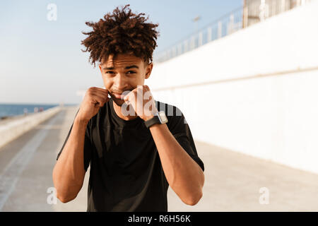 Close up of a concentrated young african sportsman standing at the beach, boxing Stock Photo