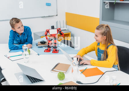 Schoolchildren programming robot together and using laptops during STEM educational class Stock Photo