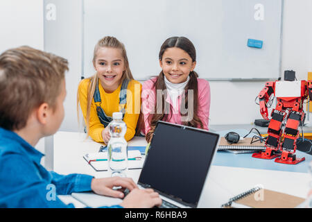 schoolchildren programming robot together and using laptop during STEM educational class Stock Photo