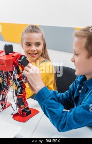 smiling schoolchildren programming robot together during STEM educational class Stock Photo