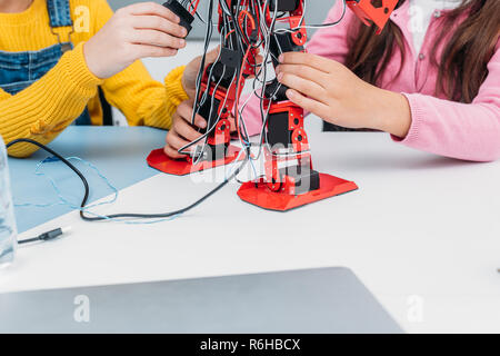 cropped view of classmates working together on robot model during STEM lesson Stock Photo