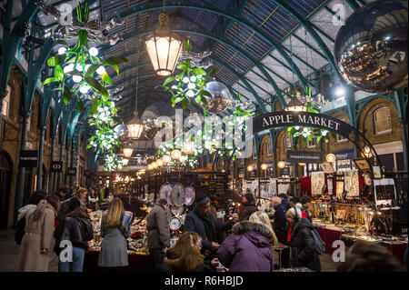 LONDON - NOVEMBER 26, 2018: Holiday shoppers browse the antiques stalls under Christmas lights of the Apple Market in Covent Garden. Stock Photo