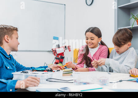 classmates sitting at table, talking and working together on project during STEM lesson Stock Photo