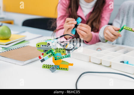 cropped view of classmates working together on project during STEM lesson with handmade robot model on foreground Stock Photo