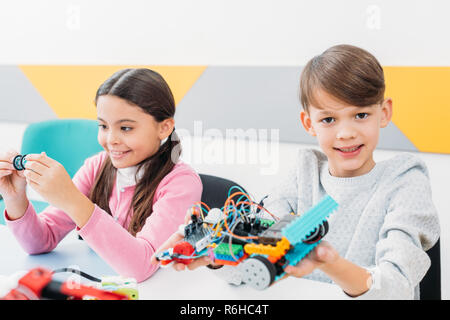 happy classmates holding robot model and working together on project during STEM lesson Stock Photo