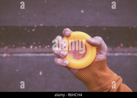 Male hand grips anti-stress rubber ring outdoors, close up Stock Photo