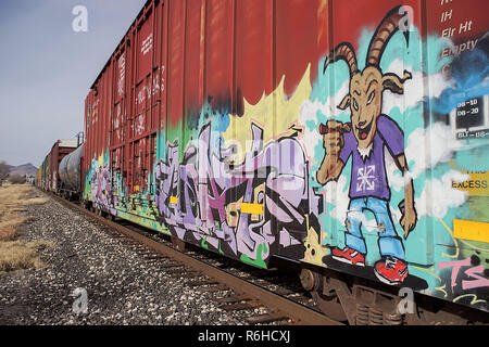 Tags and painting of a smoking humanoid with a goat head on a Union Pacific railroad box car, passing through Alpine, Texas. Stock Photo