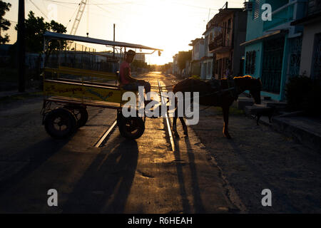 Silhouette of a horse and cart taxi with the setting sun behind in a Cienfuegos street in Cuba Stock Photo
