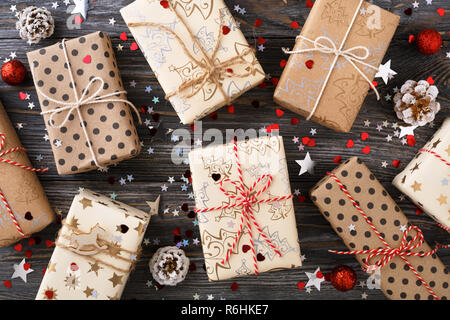 Christmas gift boxes & pine cones on decorated festive table with sparkle stars. Wrapped gifts and ribbons twine. Winter holidays. Stock Photo