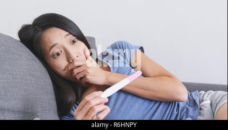 Young woman looking at pregnancy test Stock Photo